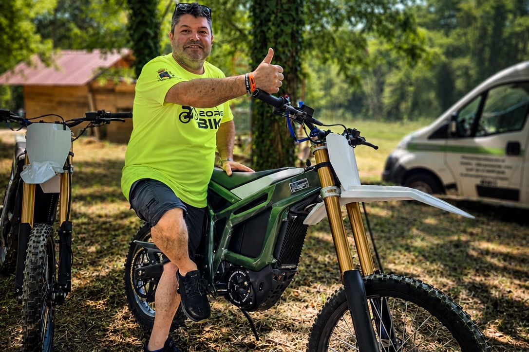 Rider sorridente con pollice in su accanto a moto elettrica Talaria